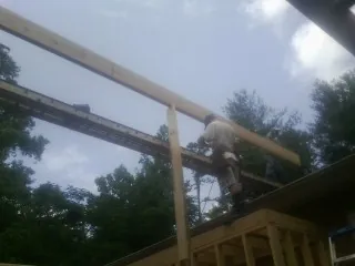 Carpenter setting a ridge beam over a new addition frame — Ice Dam Removal by Roofing Brothers in Corona Del Mar
