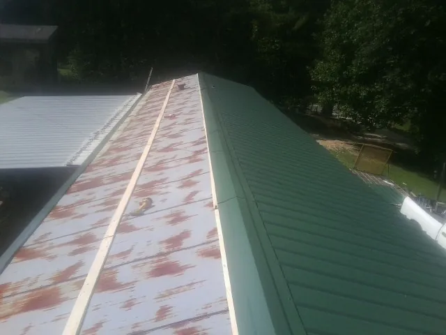 Old rusted panels beside newly installed green metal roofing — Wind Damage Roof Repair by Roofing Brothers in Corona Del Mar
