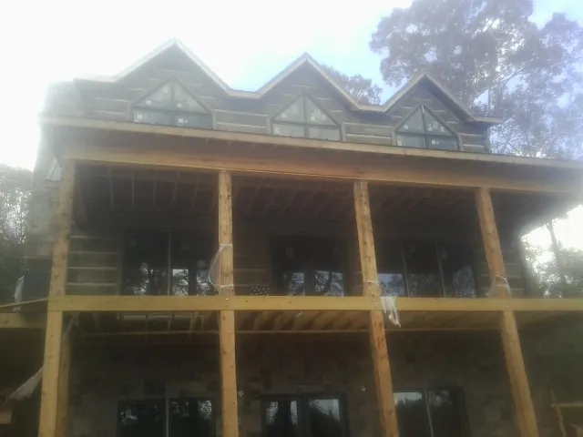 Dormers and porch framing on a large log home under construction — Roof Coating work by our crew in Corona Del Mar