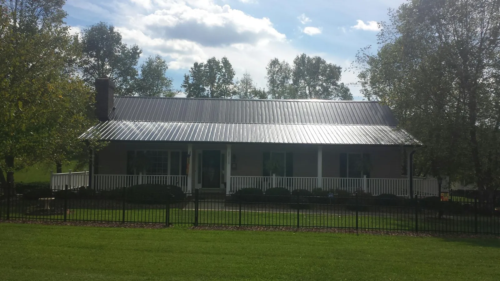 Gray metal roof on a brick ranch with a full width front porch — Gutter Guard Installation work by our crew in Corona Del Mar