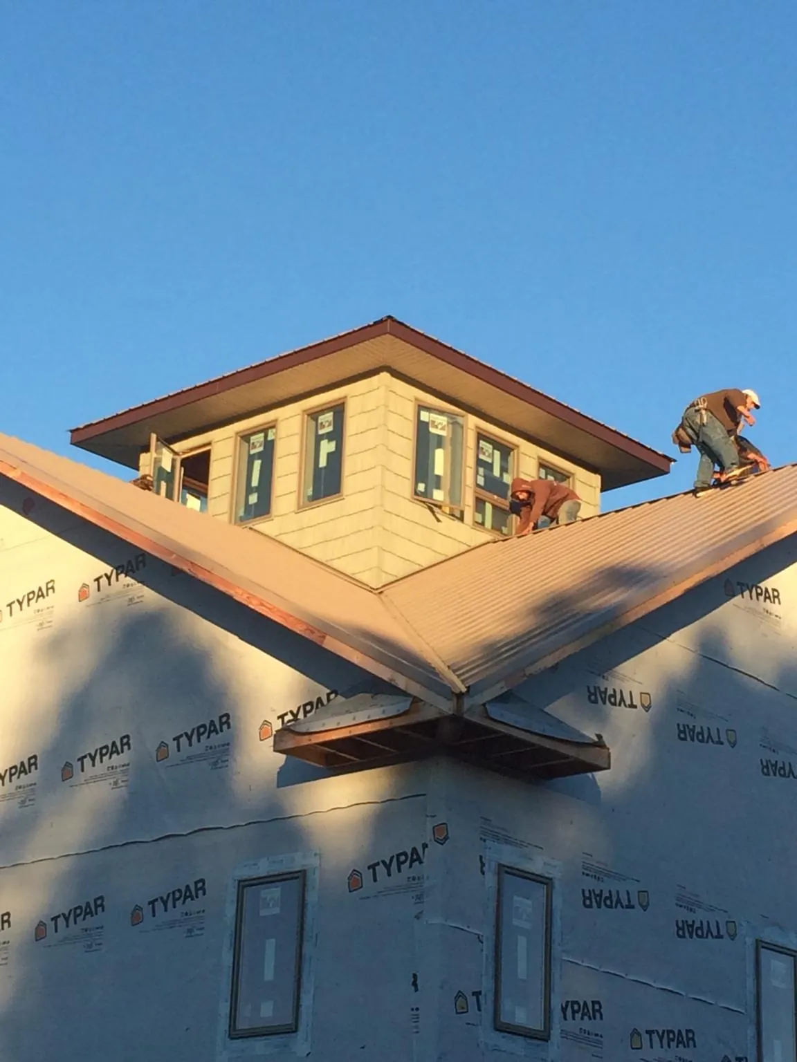 Roofers working around a rooftop cupola on a new metal roof at sunset — Roof Waterproofing in Corona Del Mar by Roofing Brothers